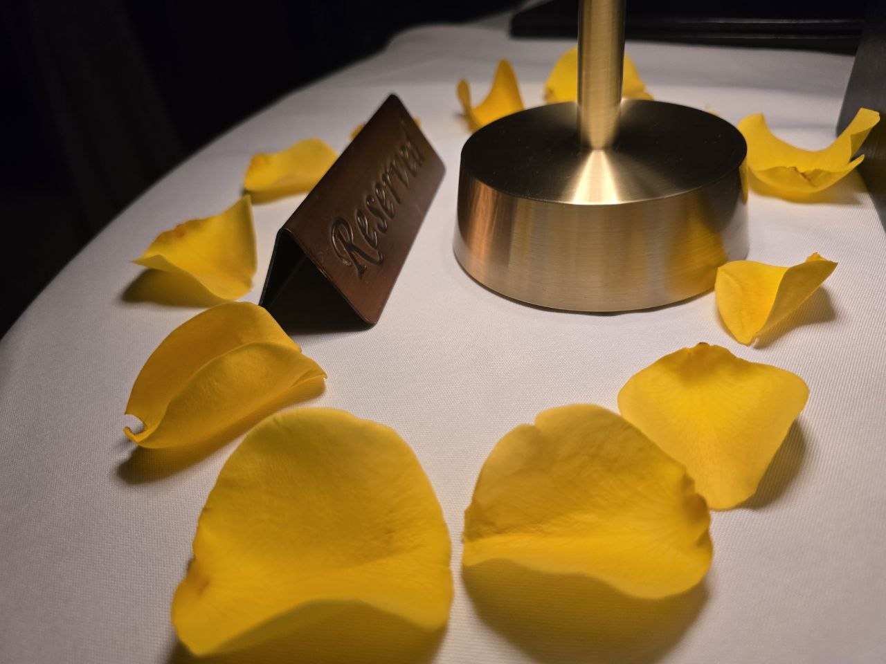 Close-up of yellow rose petals scattered around copper Reserved sign at Ocean Prime